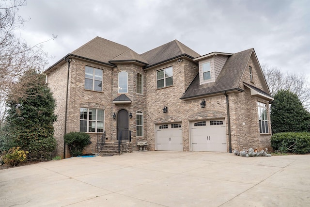 french country inspired facade featuring a garage, brick siding, driveway, and a shingled roof