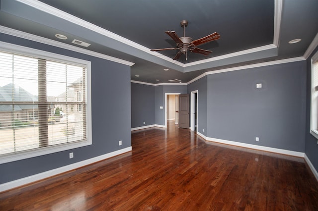 empty room featuring wood finished floors, baseboards, visible vents, a tray ceiling, and ceiling fan