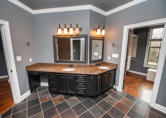 bathroom featuring double vanity, ornamental molding, baseboards, and a sink