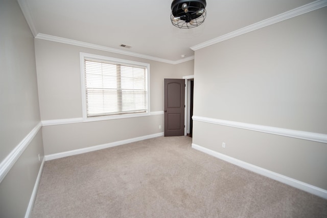 carpeted spare room with crown molding, visible vents, and baseboards