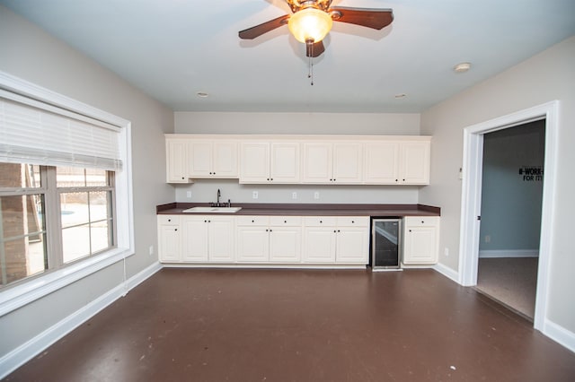 kitchen featuring dark countertops, wine cooler, baseboards, and concrete flooring