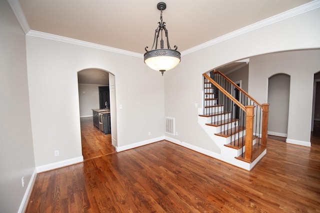 unfurnished room featuring visible vents, baseboards, stairs, wood finished floors, and arched walkways