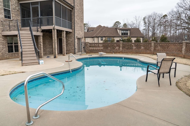 view of pool with a fenced in pool, fence, stairs, a sunroom, and a patio area