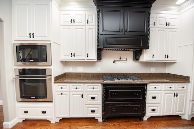 kitchen with dark stone countertops, white cabinets, appliances with stainless steel finishes, and dark wood-style flooring