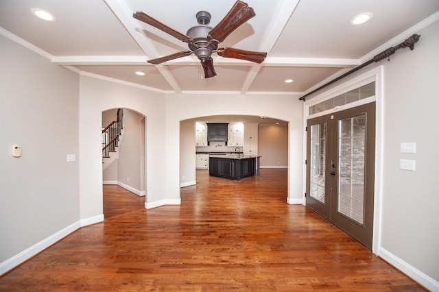 interior space with wood finished floors, baseboards, coffered ceiling, arched walkways, and french doors