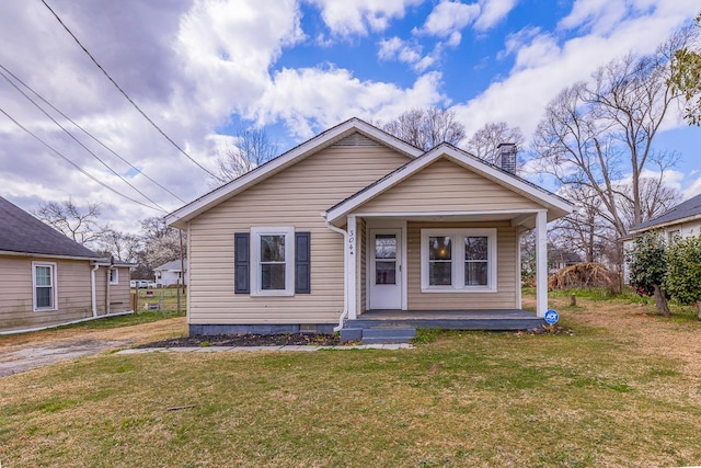 bungalow-style home with a front lawn, covered porch, and a chimney