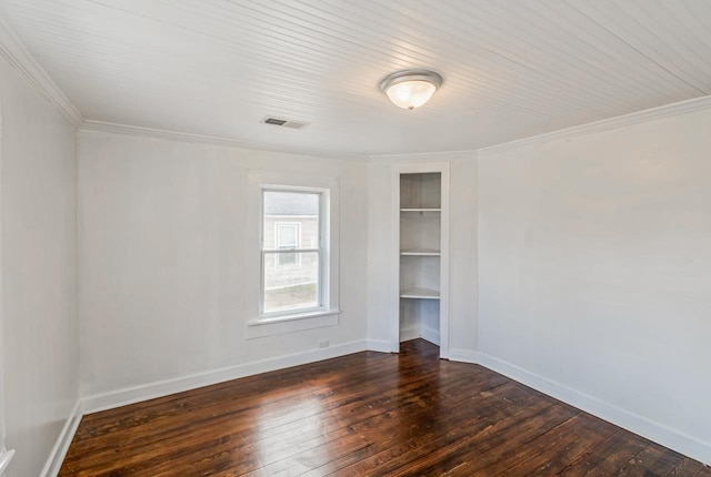 unfurnished room with visible vents, built in shelves, baseboards, ornamental molding, and dark wood-style flooring