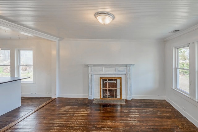 unfurnished living room featuring ornamental molding, a tile fireplace, a healthy amount of sunlight, and wood-type flooring