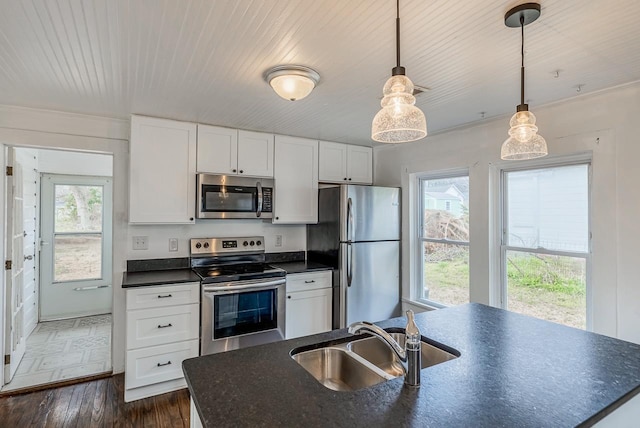 kitchen with dark wood-type flooring, a sink, dark countertops, appliances with stainless steel finishes, and white cabinets