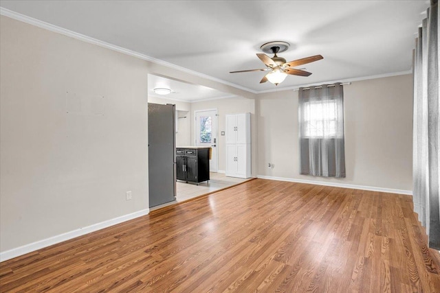 unfurnished living room with a wealth of natural light, light wood-style flooring, baseboards, and ornamental molding