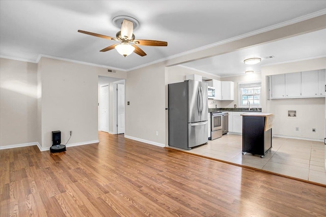 unfurnished living room with crown molding, baseboards, light wood finished floors, and ceiling fan