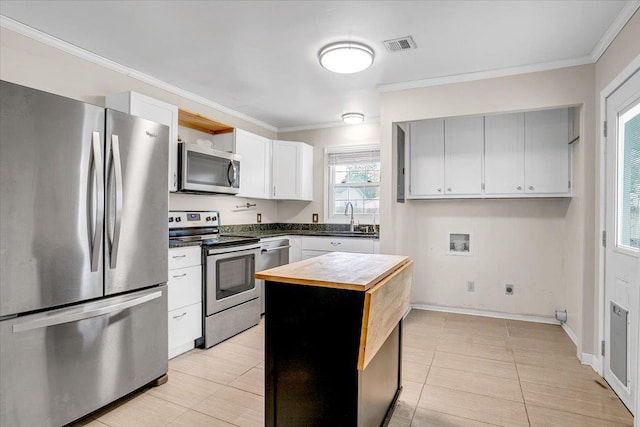 kitchen featuring visible vents, a sink, ornamental molding, stainless steel appliances, and butcher block counters