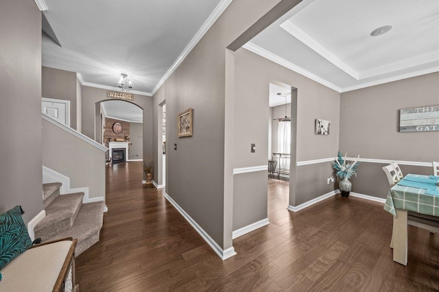 entrance foyer featuring ornamental molding, wood finished floors, arched walkways, a fireplace, and baseboards