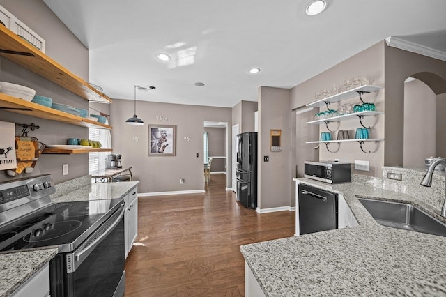 kitchen featuring open shelves, a sink, dark wood finished floors, arched walkways, and appliances with stainless steel finishes