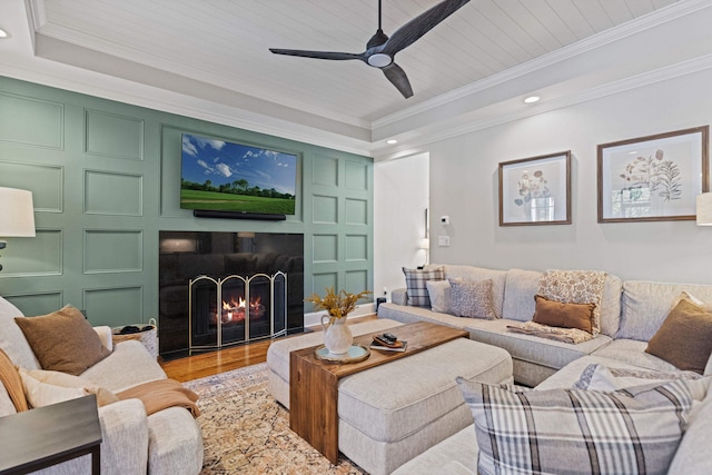 living area with a decorative wall, ornamental molding, light wood-style flooring, and a lit fireplace