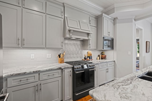 kitchen with backsplash, crown molding, black microwave, gray cabinets, and stainless steel gas stove