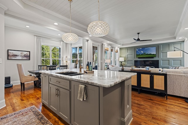 kitchen featuring a sink, a raised ceiling, open floor plan, and gray cabinetry