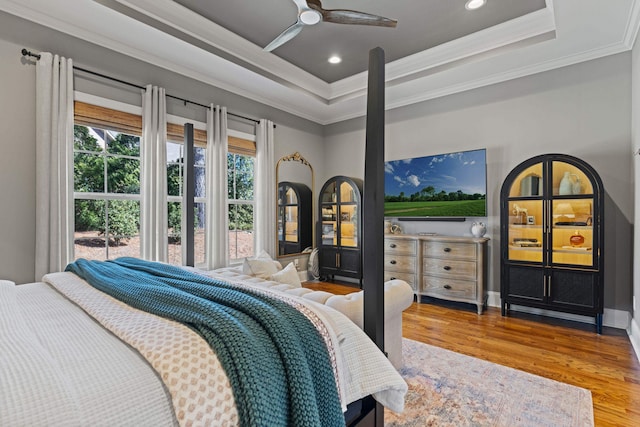 bedroom featuring a raised ceiling, wood finished floors, recessed lighting, crown molding, and baseboards