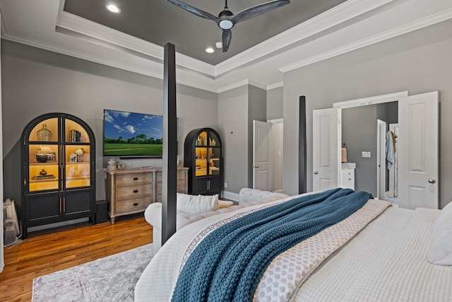 bedroom featuring ornamental molding, a tray ceiling, and wood finished floors