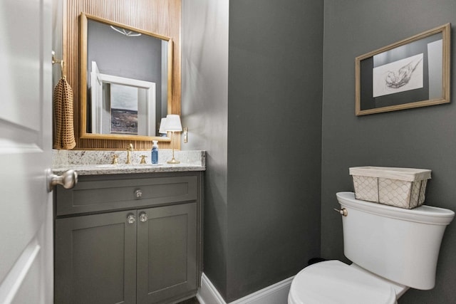 bathroom with toilet, vanity, and baseboards