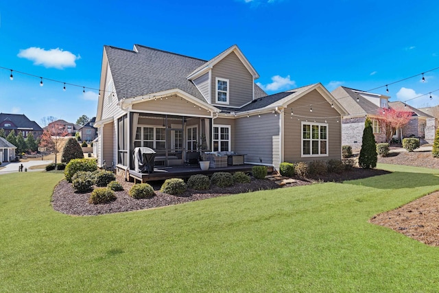 back of property featuring a lawn, roof with shingles, and a sunroom