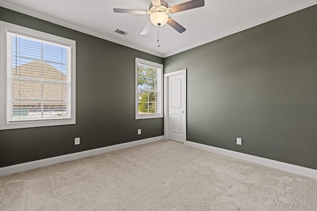 empty room with baseboards, visible vents, ceiling fan, ornamental molding, and light colored carpet