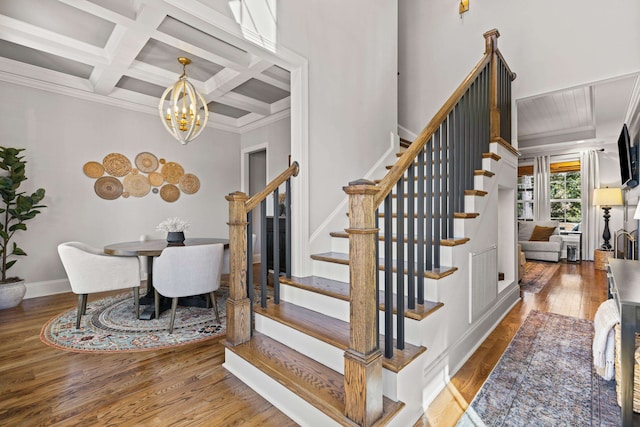 staircase featuring wood finished floors, visible vents, coffered ceiling, beam ceiling, and a notable chandelier