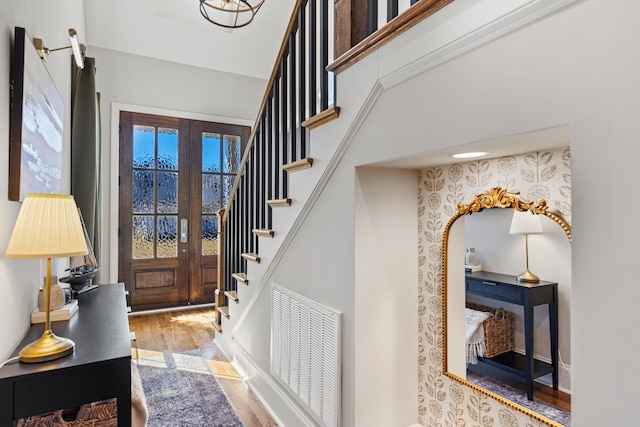 foyer entrance with visible vents, stairway, french doors, and wood finished floors