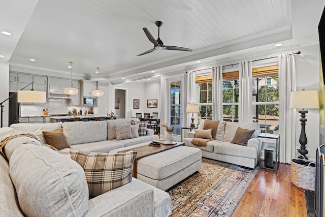 living room featuring recessed lighting, crown molding, a raised ceiling, and hardwood / wood-style flooring