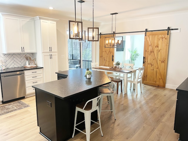 kitchen with a barn door, tasteful backsplash, dark countertops, and dishwasher