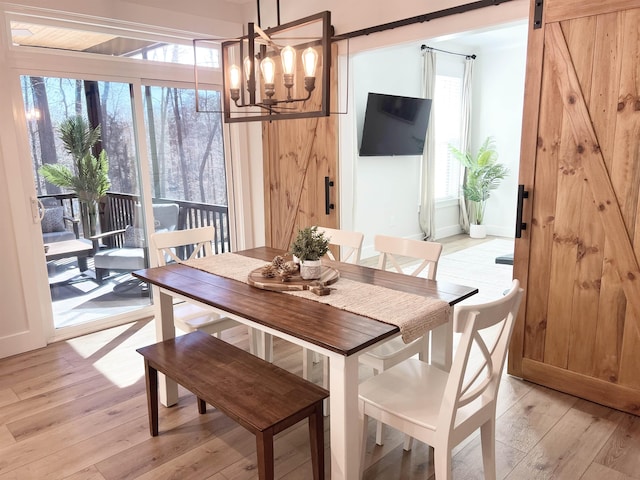 dining room featuring an inviting chandelier, a barn door, and light wood-style flooring