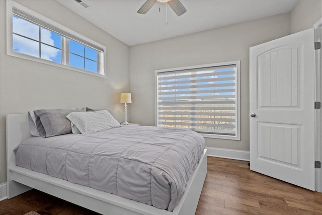 bedroom featuring visible vents, ceiling fan, baseboards, and wood finished floors