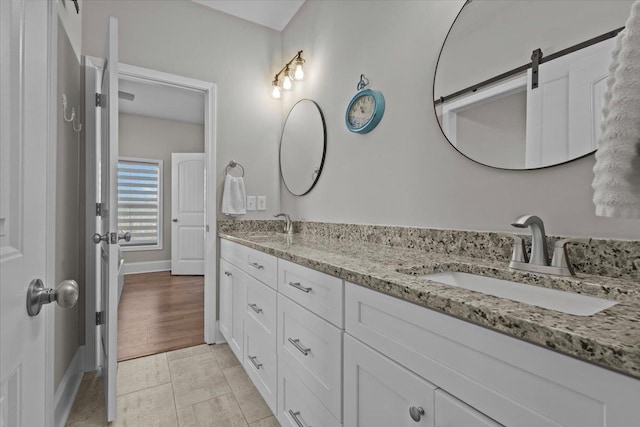 bathroom with double vanity, baseboards, and a sink