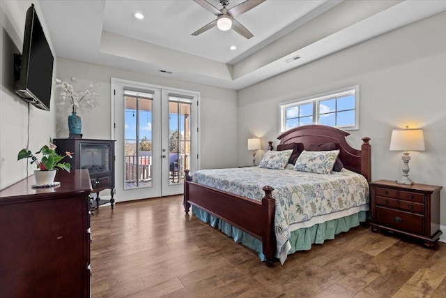 bedroom featuring french doors, a raised ceiling, dark wood finished floors, and access to outside