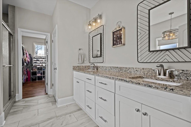 full bathroom with a sink, a walk in closet, a stall shower, and double vanity