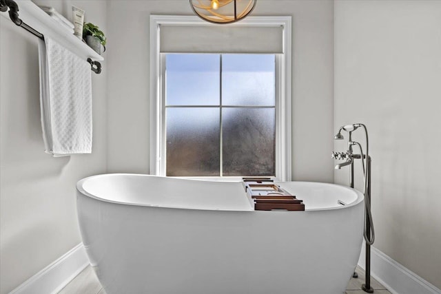 full bathroom featuring a soaking tub and baseboards