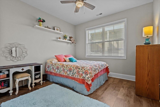 bedroom featuring visible vents, ceiling fan, baseboards, and wood finished floors