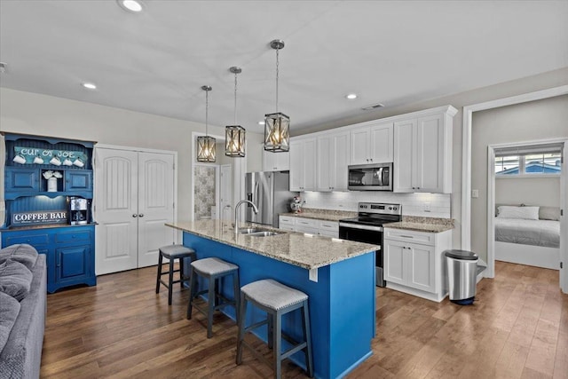 kitchen featuring a kitchen bar, backsplash, appliances with stainless steel finishes, and dark wood-style flooring