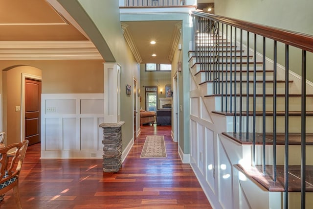 corridor with decorative columns, arched walkways, wood finished floors, and a decorative wall