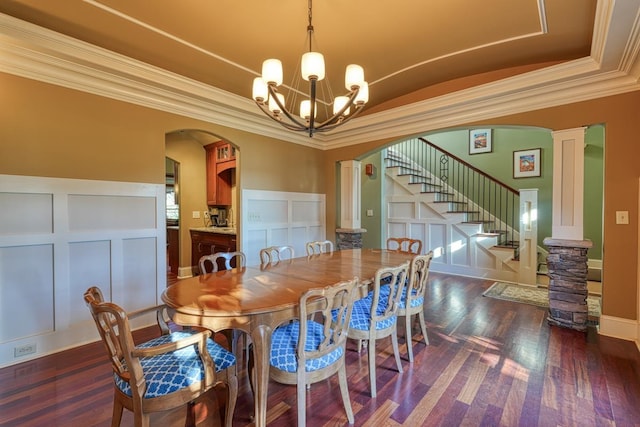 dining room featuring dark wood finished floors, stairway, ornamental molding, arched walkways, and a decorative wall