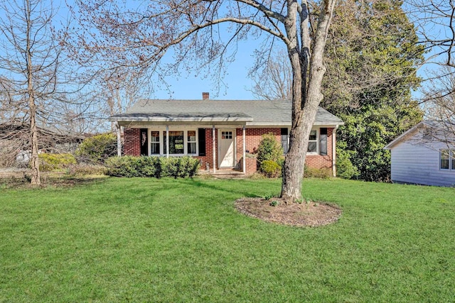 ranch-style home featuring brick siding, a chimney, and a front lawn