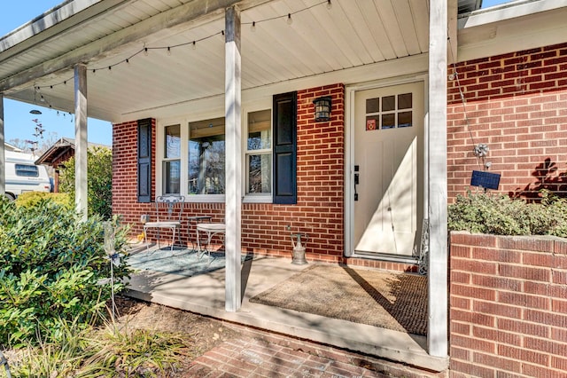 doorway to property with brick siding and covered porch