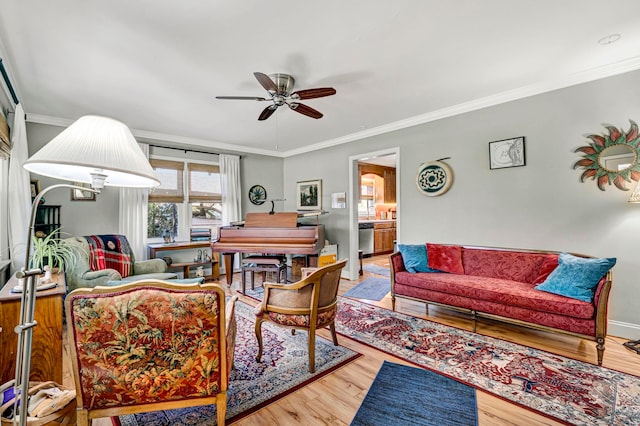 living room featuring baseboards, a ceiling fan, wood finished floors, and crown molding