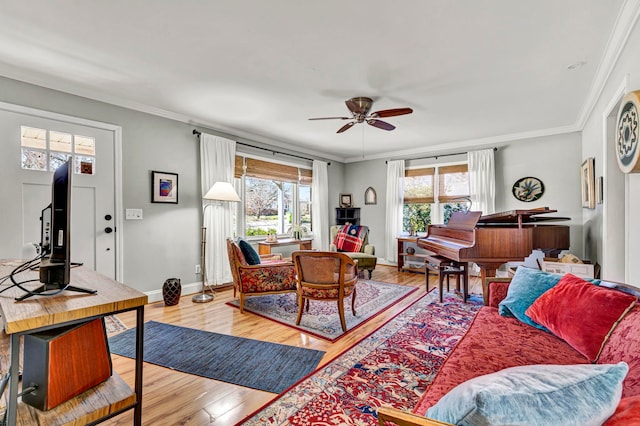 living area with a ceiling fan, crown molding, wood finished floors, and baseboards