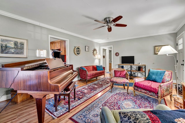 living area featuring a ceiling fan, crown molding, wood finished floors, and baseboards