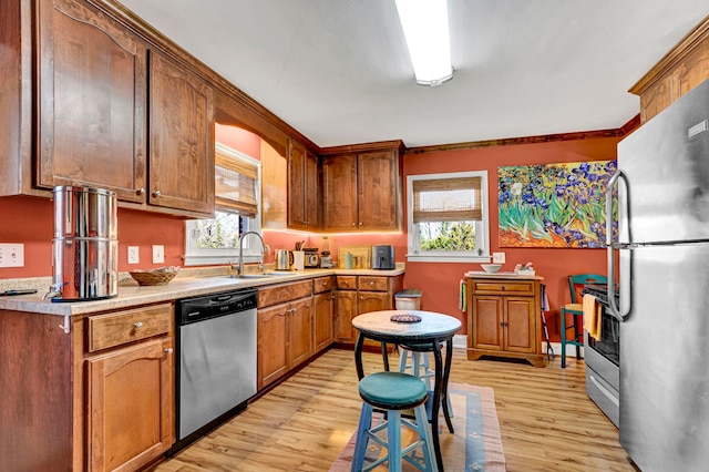 kitchen featuring a sink, light wood-style floors, appliances with stainless steel finishes, and light countertops