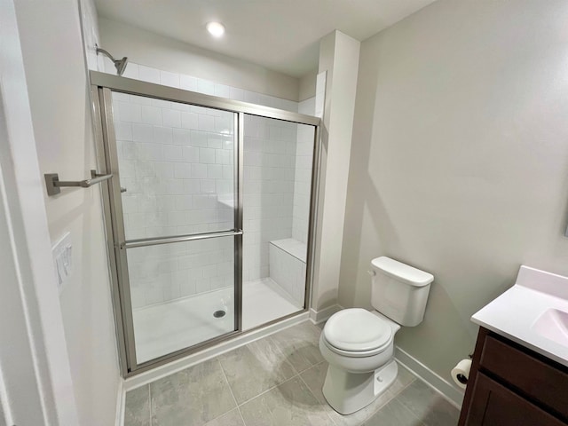 full bathroom featuring baseboards, toilet, a stall shower, and vanity