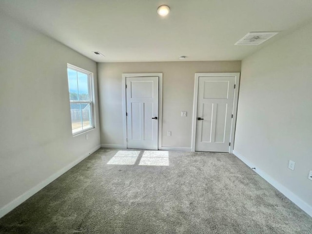 unfurnished bedroom featuring baseboards, carpet floors, and visible vents