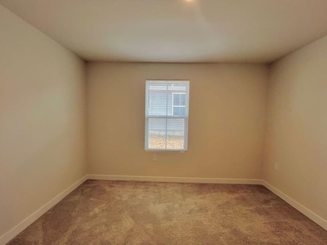 carpeted spare room featuring baseboards