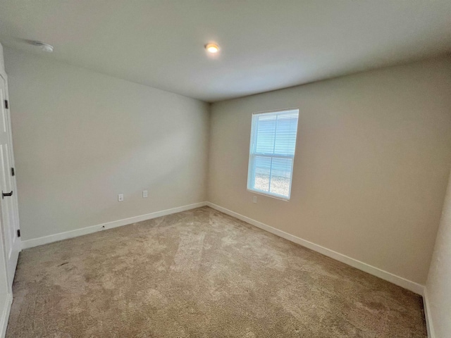 empty room with light colored carpet and baseboards